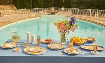 Table devant une piscine avec de la vaisselle du designer Alexandre Benjamin x Monoprix