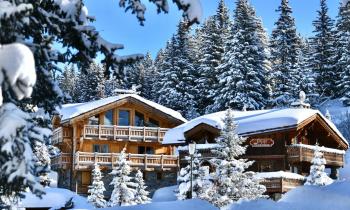 Chalet sous la neige entouré de sapins