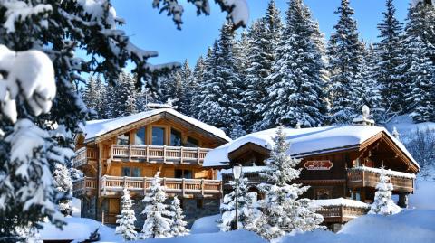Chalet sous la neige entouré de sapins