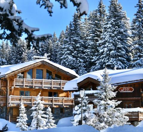 Chalet sous la neige entouré de sapins